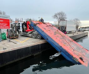 Barge is pulled out of the water onto a quay. 